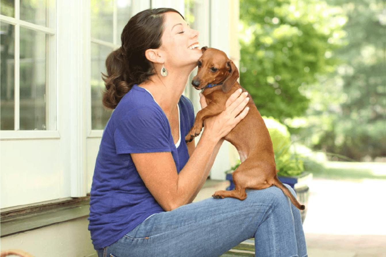 Image of woman holding a small red dachshund dog